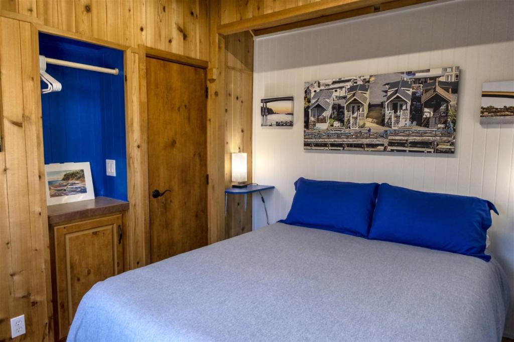 a bedroom with a blue bed and wooden walls at H - Harbor Watch in Fort Bragg