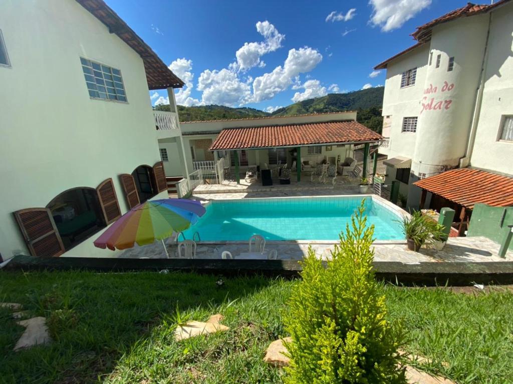 Una piscina con una sombrilla al lado de una casa. en Pousada do Solar, en São Lourenço