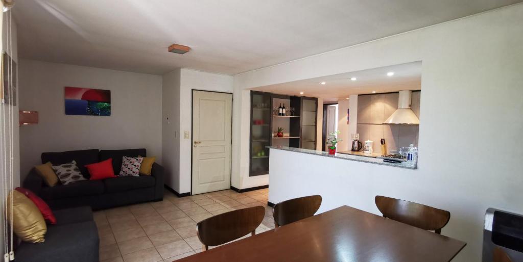 a kitchen and a living room with a table and a couch at Belgrano Apartment con cochera in Mendoza