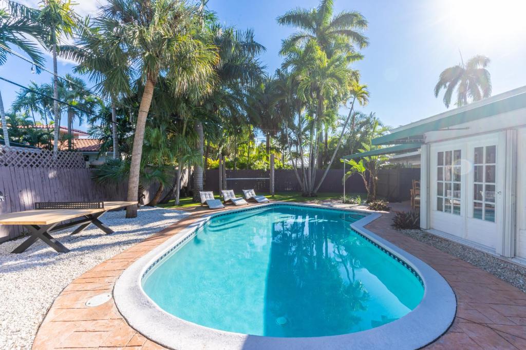 a swimming pool in a backyard with palm trees at NEWLY RENOVATED POOL, HOT TUB, & EPIC BACKYARD in Fort Lauderdale