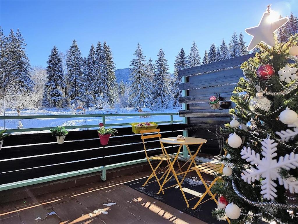 a porch with a christmas tree and a table at The Evergreen Nest - Silver Mountain in Poiana Brasov