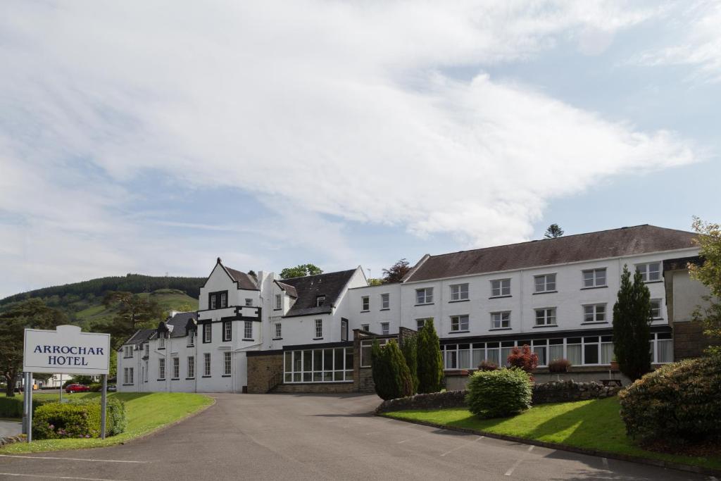 ein großes weißes Gebäude mit einem Schild davor in der Unterkunft Arrochar Hotel 'A Bespoke Hotel' in Arrochar