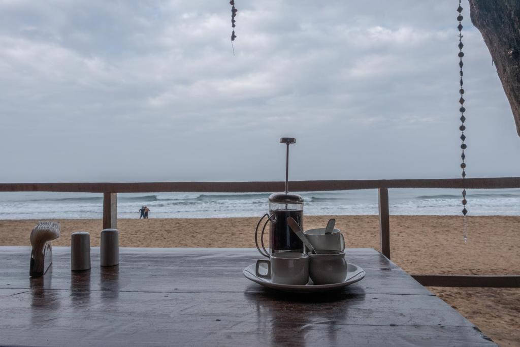 a table with cups and utensils on the beach at Jardim a Mar in Agonda