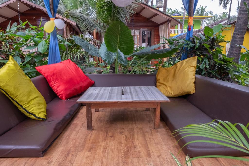 a couch with colorful pillows and a coffee table at Jardim a Mar in Agonda