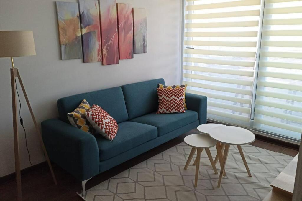 Sofá azul en la sala de estar con mesa en Departamento Nuevo en Condominio Viña del Mar en Viña del Mar