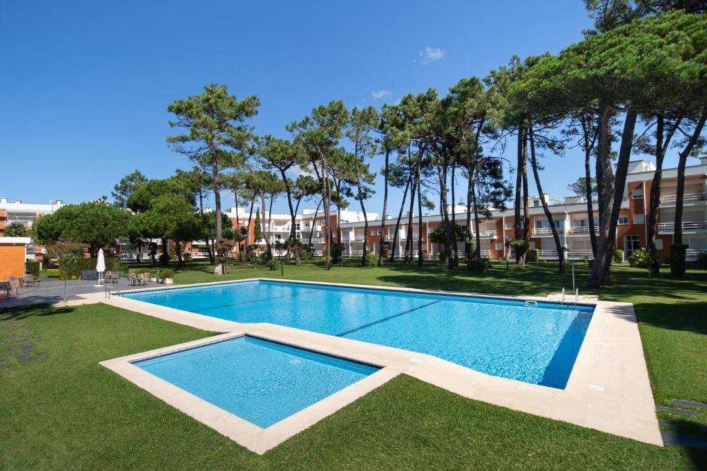 a swimming pool in the middle of a yard with trees at Casa do Suave Mar in Esposende