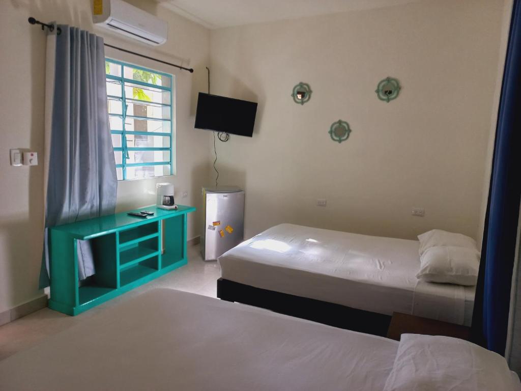 a hotel room with two beds and a television at Bea rooms and studios in Cozumel