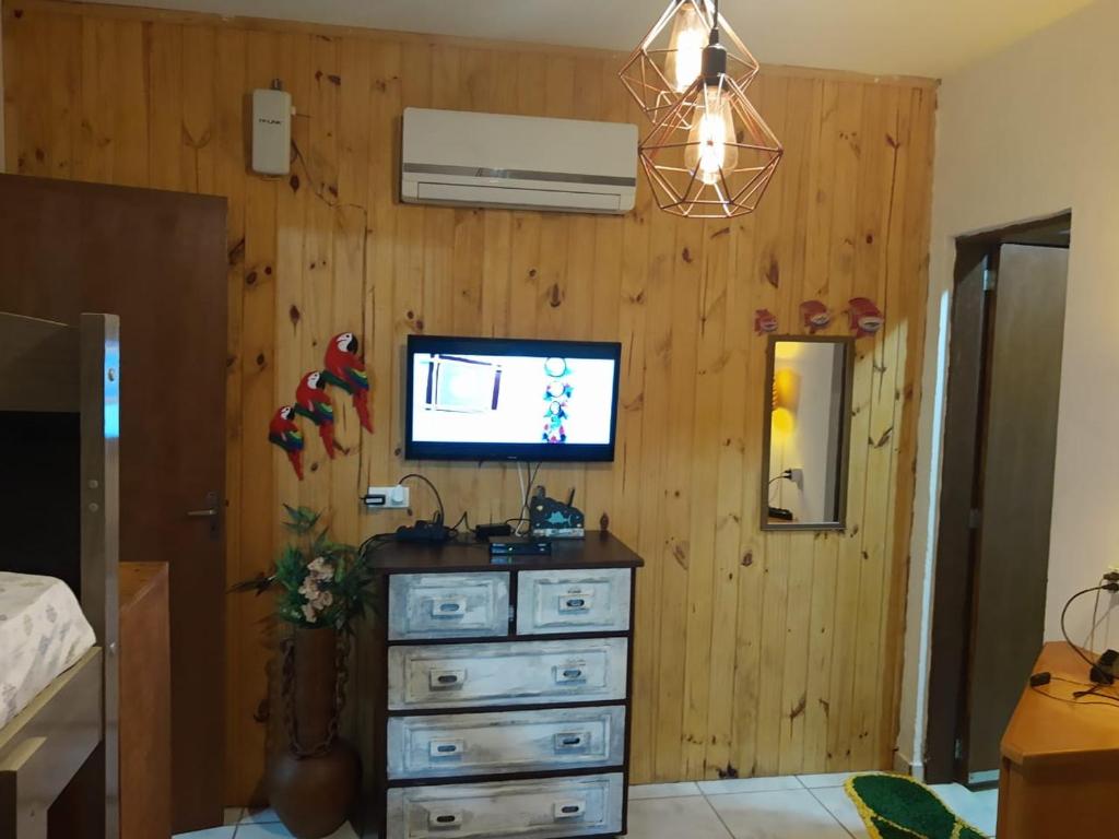 una camera da letto con cassettiera e TV su una parete in legno di Flat Filtro Dos Sonhos a Ilhabela