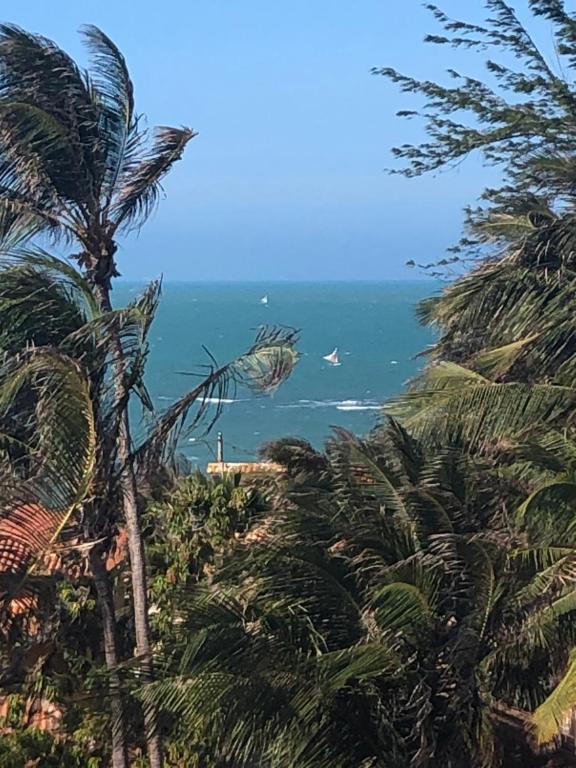 a view of the ocean through palm trees at Bela Vista in Canoa Quebrada