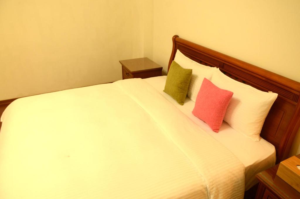 a bedroom with a white bed with two colorful pillows at East of Love Homestay in Hualien City