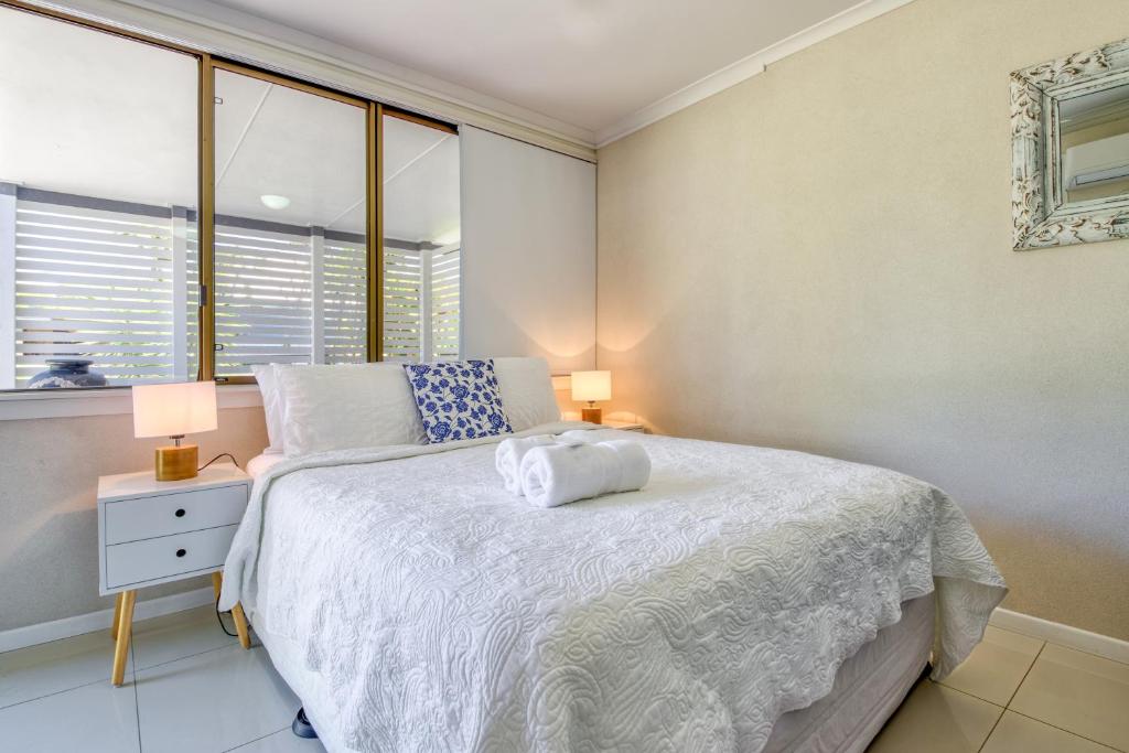 a bedroom with a white bed with two lamps and a window at Little Salty Vibes in Rainbow Beach