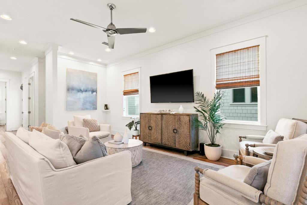 a living room with white furniture and a flat screen tv at Family Tides in Santa Rosa Beach