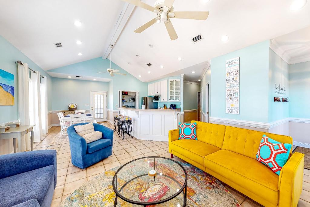 a living room with a yellow couch and a table at Ripplin Sands in Dauphin Island
