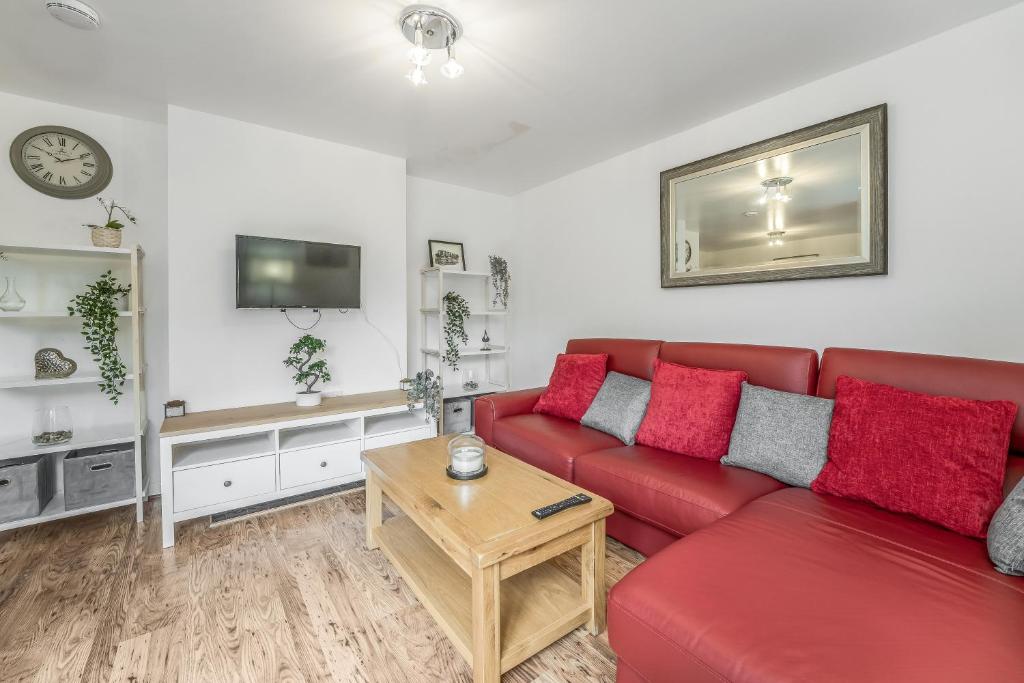 a living room with a red couch and a table at Spacious 3 Bedroom Modern House - Heart of Edinburgh - Private Main Door Entrance & Private Garden with Stunning Views of Arthur Seat in Edinburgh