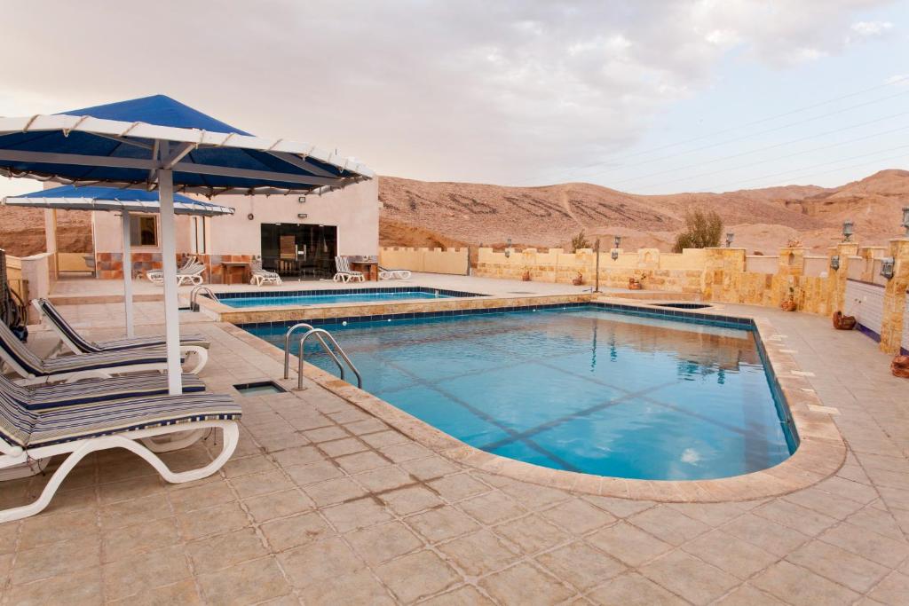 a swimming pool with a chair and an umbrella at Arab Divers Dive Center and Bed & Breakfast in Aqaba