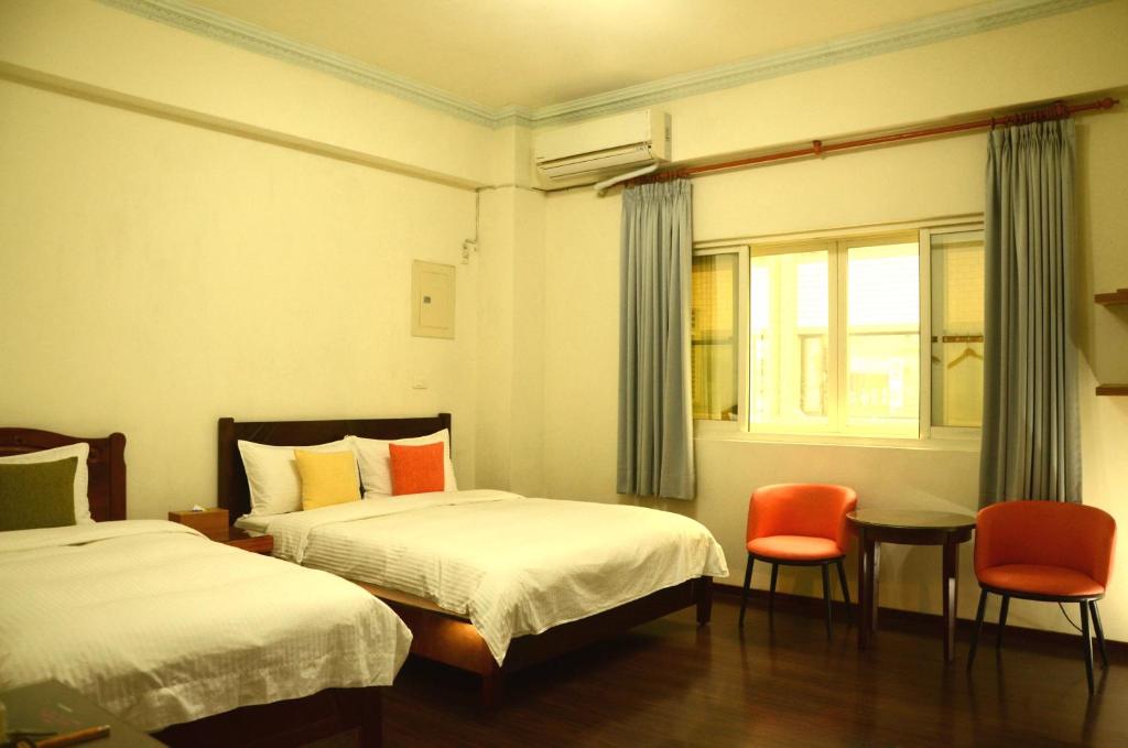 a hotel room with two beds and a table and chairs at East of Love Homestay in Hualien City