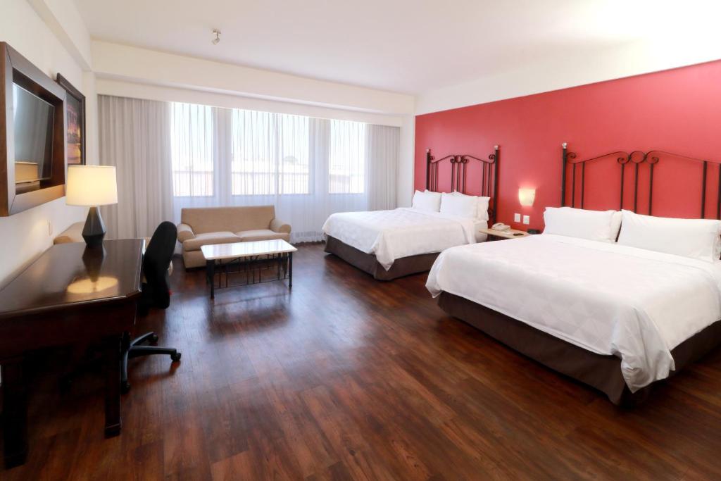 a hotel room with two beds and a desk at Holiday Inn Hotel & Suites Centro Historico, an IHG Hotel in Guadalajara
