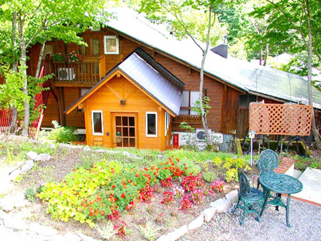 a house with a flower garden in front of it at Pension Buddy in Kitashiobara