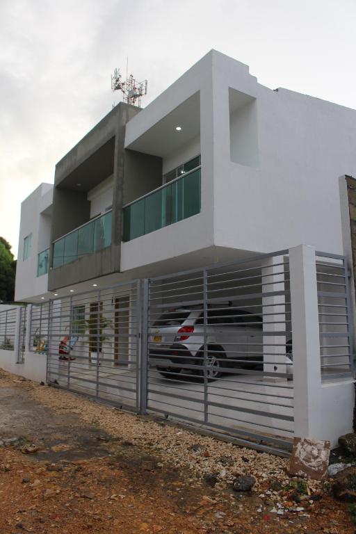 ein weißes Gebäude mit einer Garage mit einem Auto darin in der Unterkunft Mar y Tierra in Coveñas