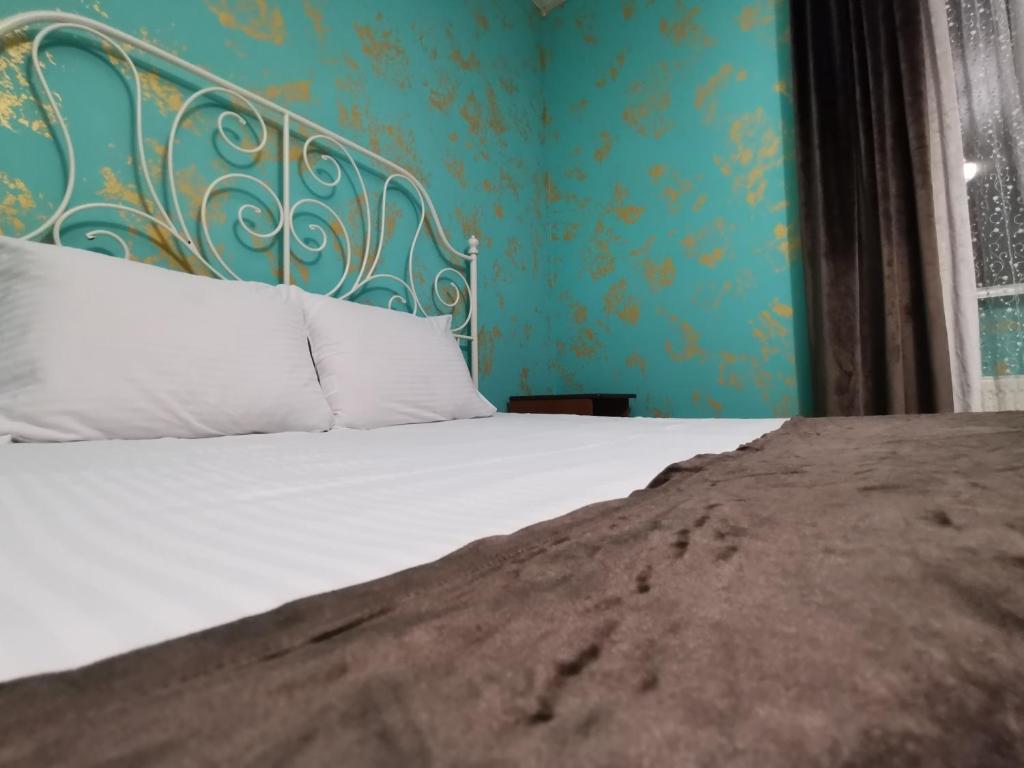 ゲレンジークにあるIzumrud Guest Houseの白いシーツと青い壁のベッド