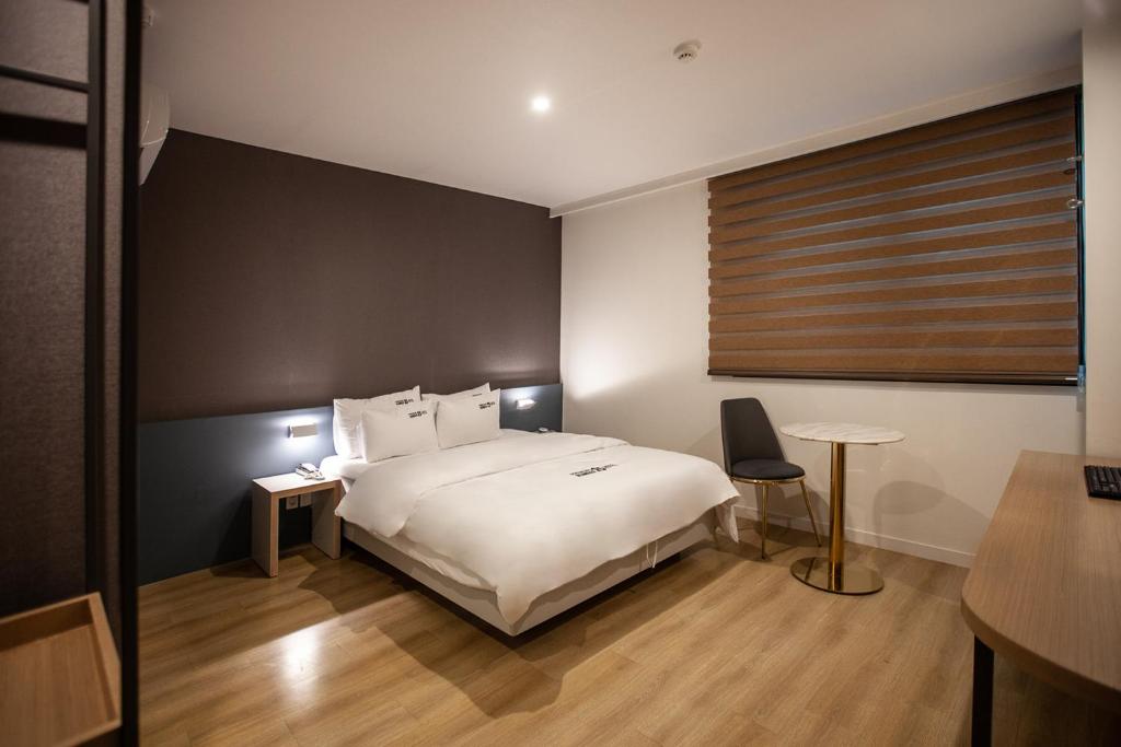 Un dormitorio con una gran cama blanca y una mesa en No.25 Hotel Busan Seomyeon Station en Busan