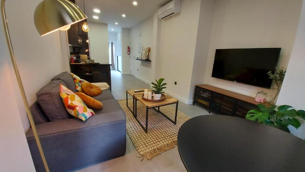 sala de estar con sofá y TV de pantalla plana en Apartamento Golddem City en Málaga