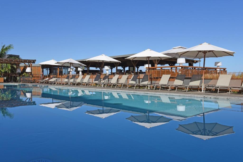 a swimming pool with chairs and umbrellas at Dina Morgabine Saint Gilles in Saint-Gilles-les-Bains