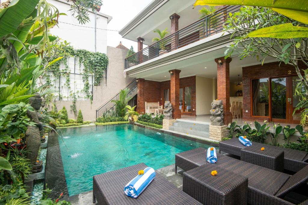 a swimming pool in front of a building with a house at Villa Semujan Ubud in Ubud