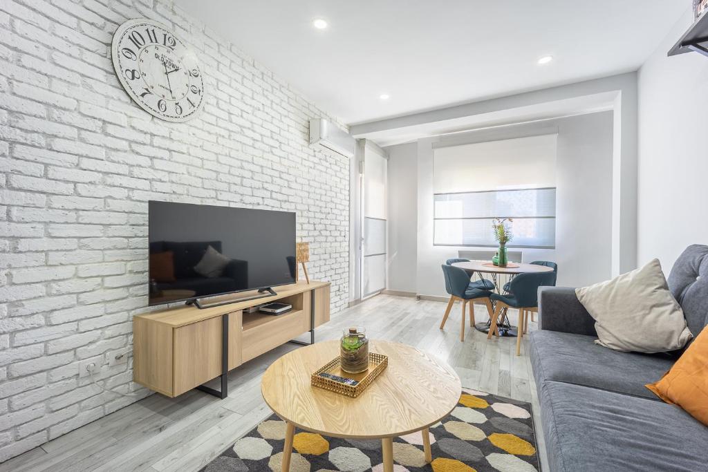 - un salon avec une télévision et un mur en briques dans l'établissement Delagua Apartments Atocha I, à Madrid
