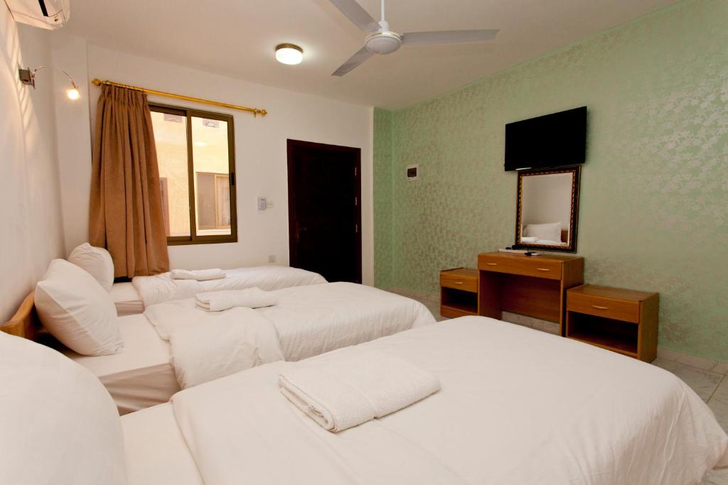 a hotel room with three beds and a mirror at Arab Divers Dive Center and Bed & Breakfast in Aqaba