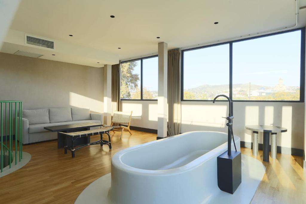 a large bathroom with a tub and a living room at Hotel Zeg in Tbilisi City