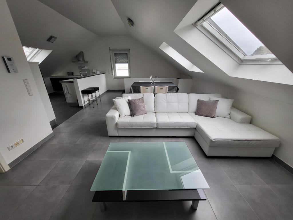 sala de estar con sofá blanco y mesa de cristal en COSYLOFT APARTMENT, en Boevange-sur-Attert