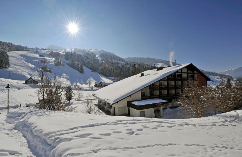 ein schneebedecktes Gebäude mit Sonne im Hintergrund in der Unterkunft Berg & Bett Säntis Lodge in Unterwasser