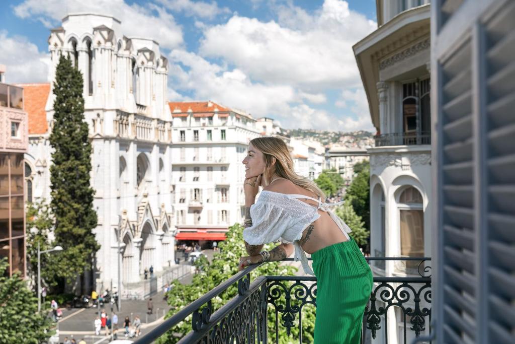 Best Western Hotel Lakmi Nice في نيس: امرأة تقف على شرفة تطل على مدينة