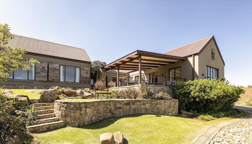 a house with a stone wall in front of it at Walkersons Estate Red Oak Ridge in Dullstroom