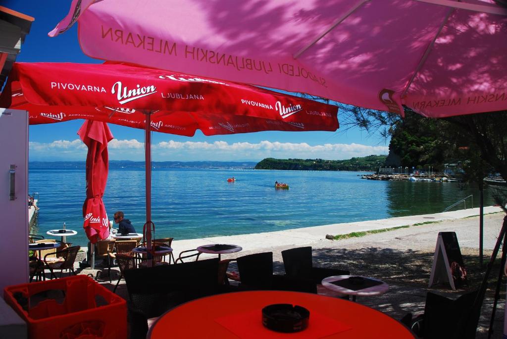 a beach with tables and umbrellas and a body of water at Hotel Fiesa in Piran