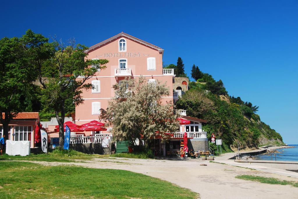 a pink building on a hill next to the ocean at Hotel Fiesa in Piran