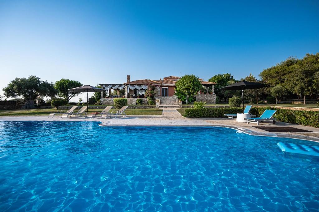 a large pool with blue water in front of a house at Villa Belvedere in Agios Andreas