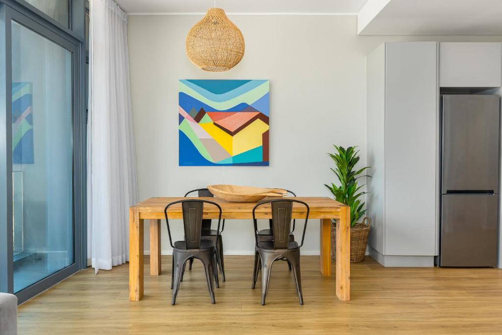 een eettafel met 4 stoelen en een schilderij bij The Axis Luxury Apartments in Kaapstad
