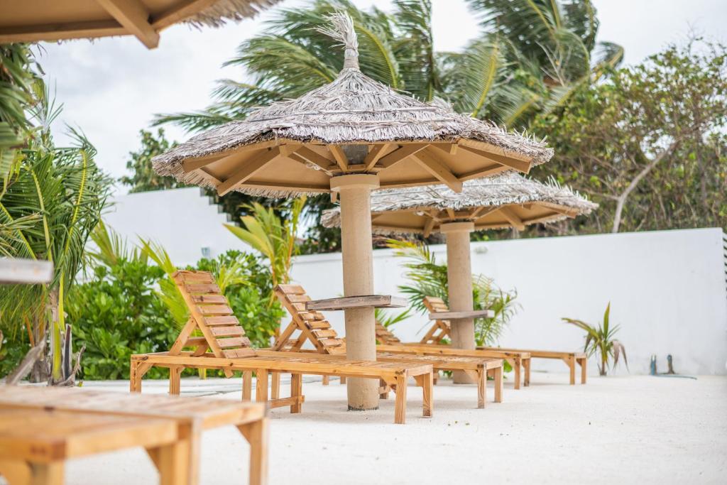 eine Reihe von Stühlen und Sonnenschirmen am Strand in der Unterkunft True South in Maradhoofeydhoo