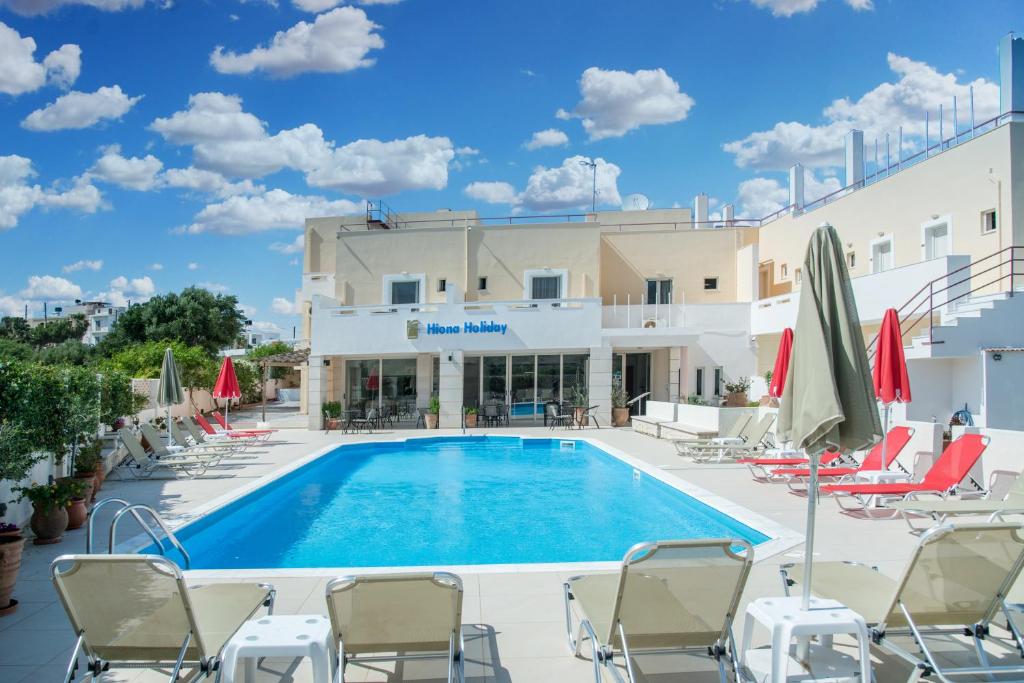 una piscina en un hotel con sillas y sombrillas en Hiona Holiday Hotel, en Palaikastro