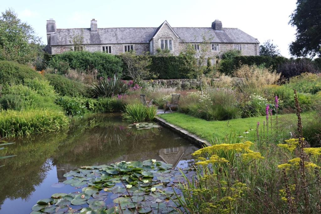 Sortridge Manor - Leat House في تافيستوك: حديقة بها بيت وبركة بها زنبق