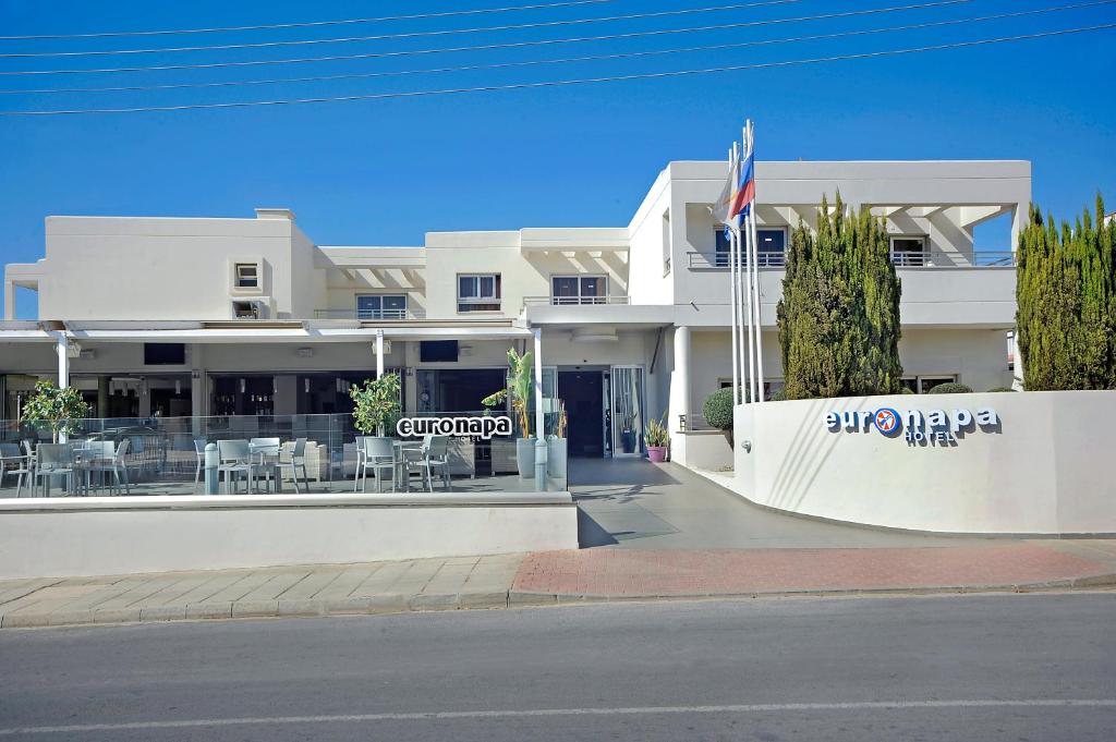 a white building with a flag in front of it at Euronapa Hotel Apartments in Ayia Napa