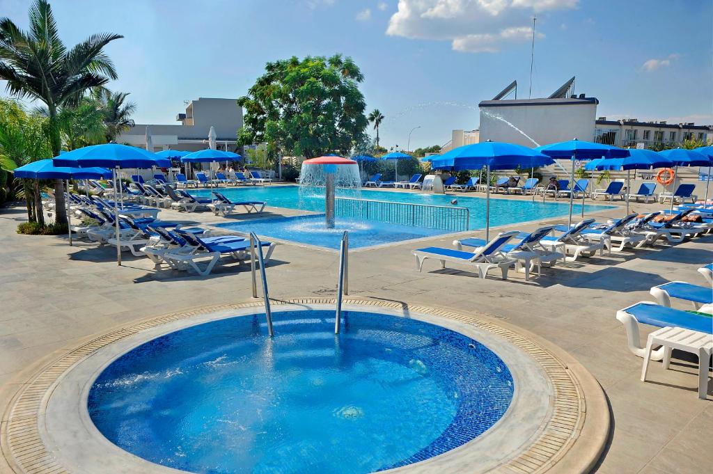 a pool with chairs and umbrellas and a swimming pool at Euronapa Hotel Apartments in Ayia Napa