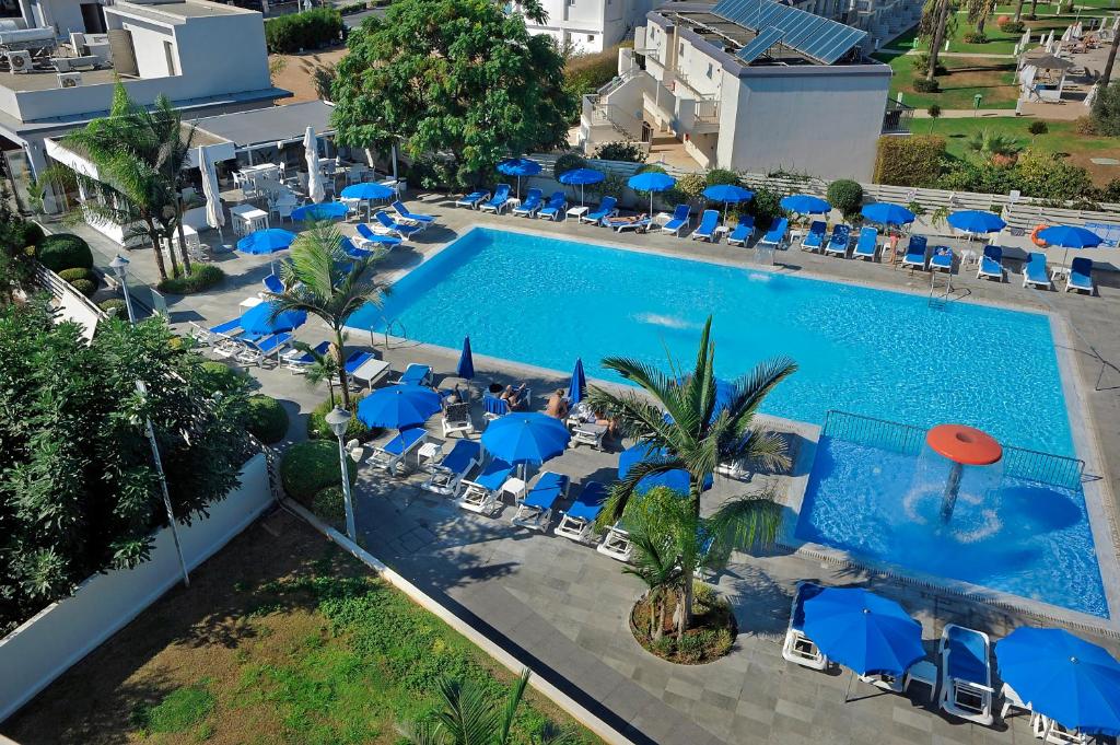 an overhead view of a swimming pool with blue umbrellas and chairs at Euronapa Hotel Apartments in Ayia Napa