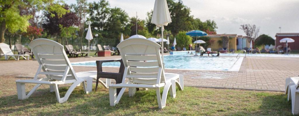 dos sillas y una mesa frente a una piscina en Centro Vacanze - Garden River, en Altidona