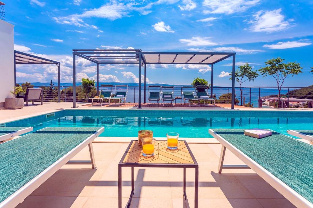 einen Pool mit zwei Gläsern Orangensaft auf zwei Tischen in der Unterkunft Seaview holiday home Lemona in Duće