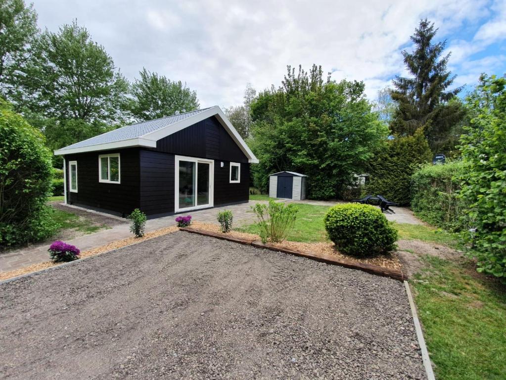 a black tiny house with a gravel driveway at Vakantiehuis, Camping Alkenhaer in Appelscha