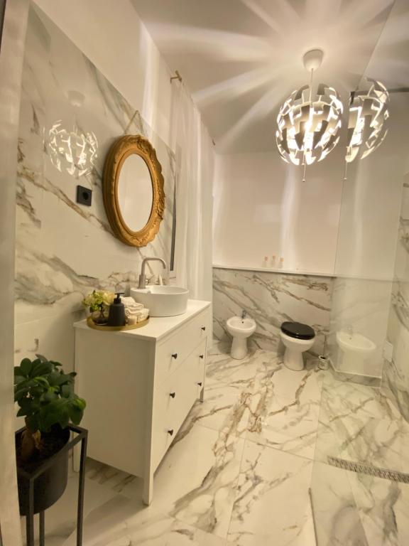 a white bathroom with a sink and a mirror at Berg Apartment in Braşov