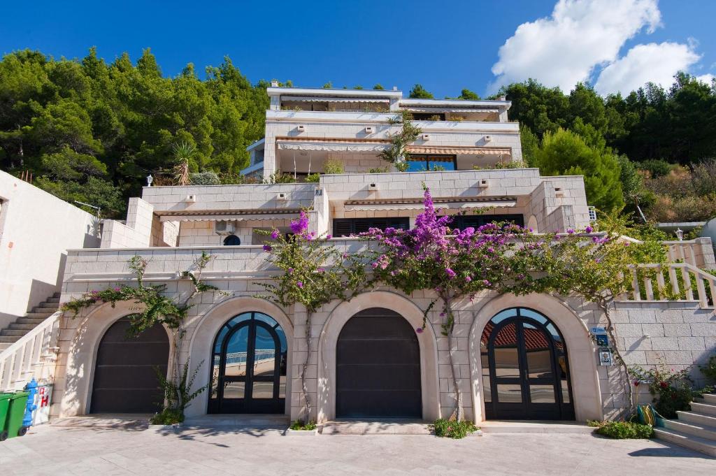 a building with purple flowers on top of it at Apartmani D&D Sosič in Brela